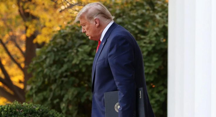 former President Donald Trump walks outside the White House holding a black folder with