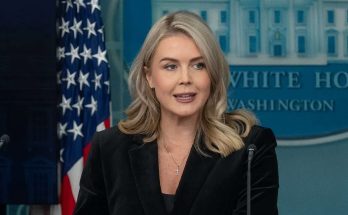 white House Press Secretary Karoline Leavitt speaking at podium with American flag and