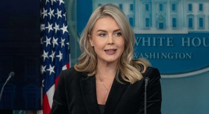 white House Press Secretary Karoline Leavitt speaking at podium with American flag and