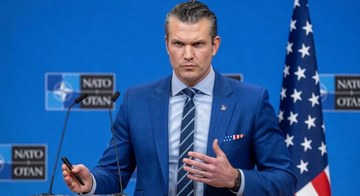 pete Hegseth stands at a podium at a NATO press conference, holding a pen, with an